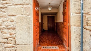 A hallway with stone walls, wooden doors, and a tiled floor. - Stay in Historic Laguardia, Sleeps 8 (Laguardia)