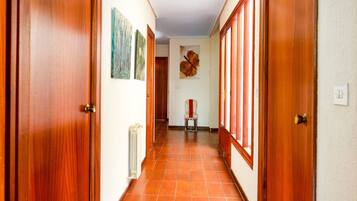 Un corridoio con porte in legno, pavimento piastrellato e opere d'arte alle pareti.