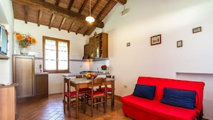 A compact living space with a kitchen, dining area, and a red sofa. - Agriturismo Tuscany with Panoramic Pool (Castiglion Fiorentino)