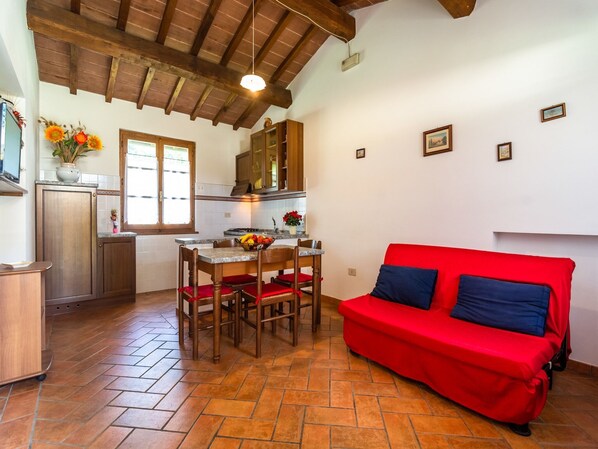 A compact living space with a kitchen, dining area, and a red sofa.