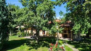 A courtyard with a stone pathway, a gazebo, and a building with a tiled roof. - Agriturismo Tuscany with Panoramic Pool (Castiglion Fiorentino)