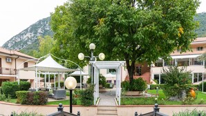 A hotel entrance with a covered walkway, a large tree, and a mountain in the background. - Countryside home in Foligno (Foligno)