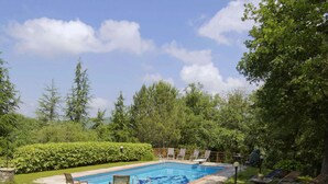 A backyard with a swimming pool, lounge chairs, and a well-maintained lawn. - Apartment in Radda with Garden (Radda in Chianti)