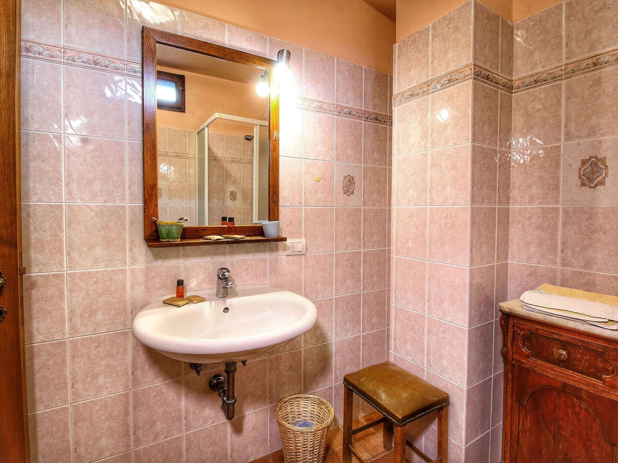 A bathroom with a sink, mirror, and wooden cabinet.