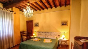A cozy bedroom with a wooden ceiling, a green bedspread, two bedside lamps, and a wooden dresser. - Apartment in Radda with Garden (Radda in Chianti)