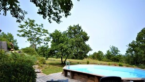 Una terraza de madera con piscina, dos sillas y un sillón de madera.