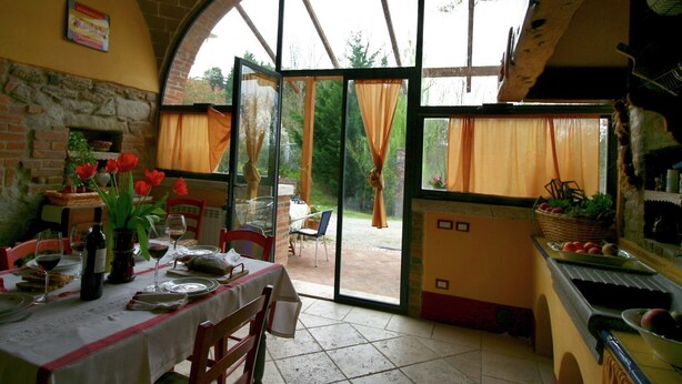 Ein Essbereich mit Tisch für zwei Personen, einem Kamin aus Ziegelsteinen und Blick durch große Fenster.