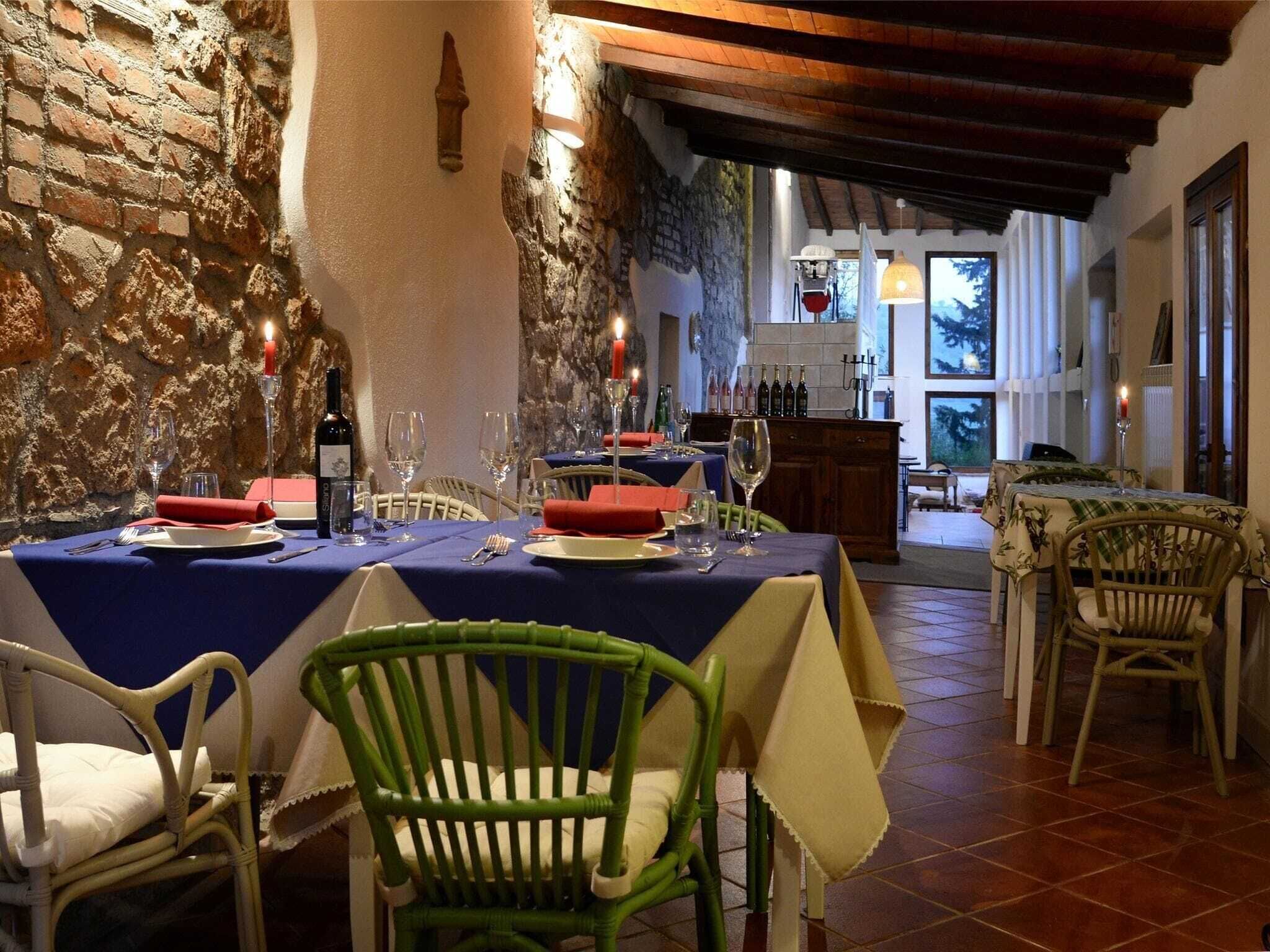 A restaurant with stone walls, wooden beams, and tables set for dining.