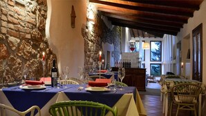 Een restaurant met stenen muren, houten balken en gedekte tafels.