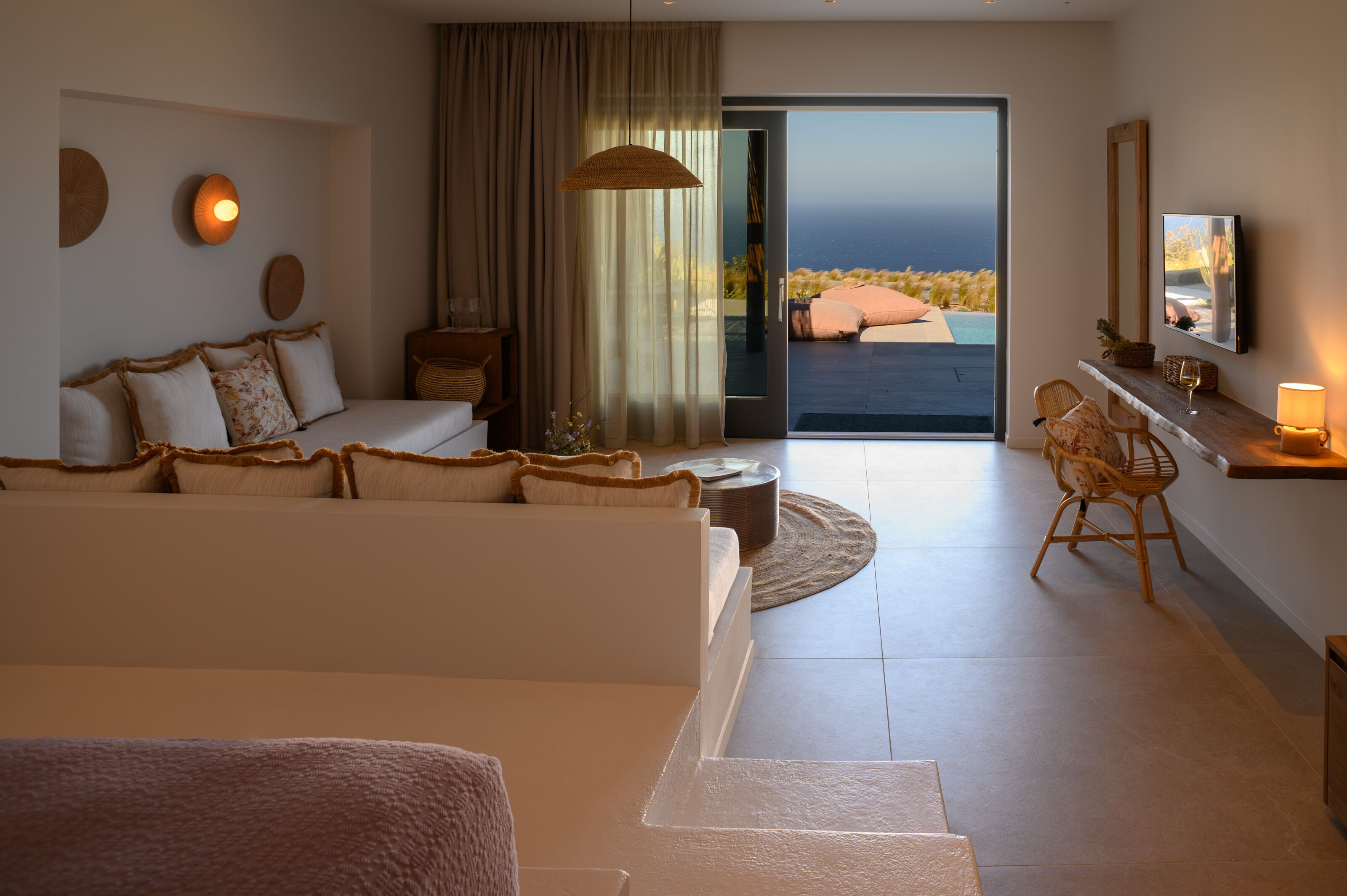 A modern living room with a sofa, a dining area, and a view of the ocean.