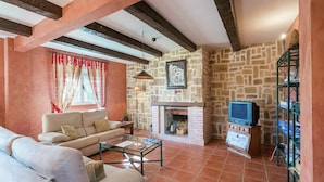 A living room with a stone fireplace, a sofa, a coffee table, and a television.