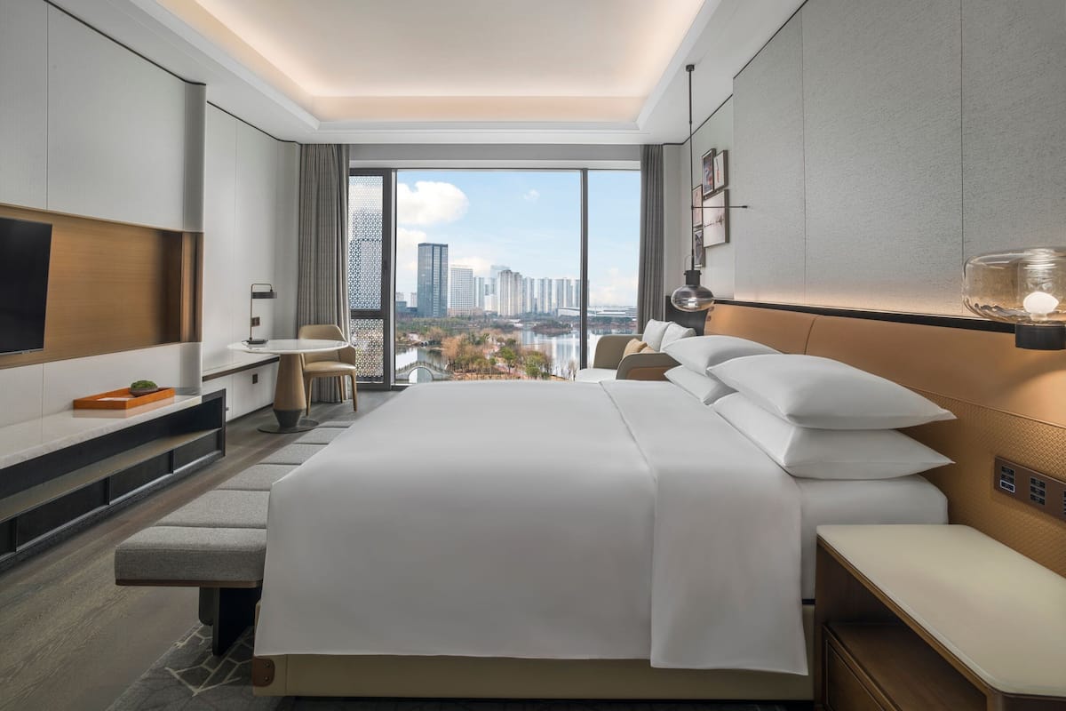 Camera d'albergo moderna con un letto grande, una scrivania e una TV. Dalle ampie finestre si gode di vista sulla città.