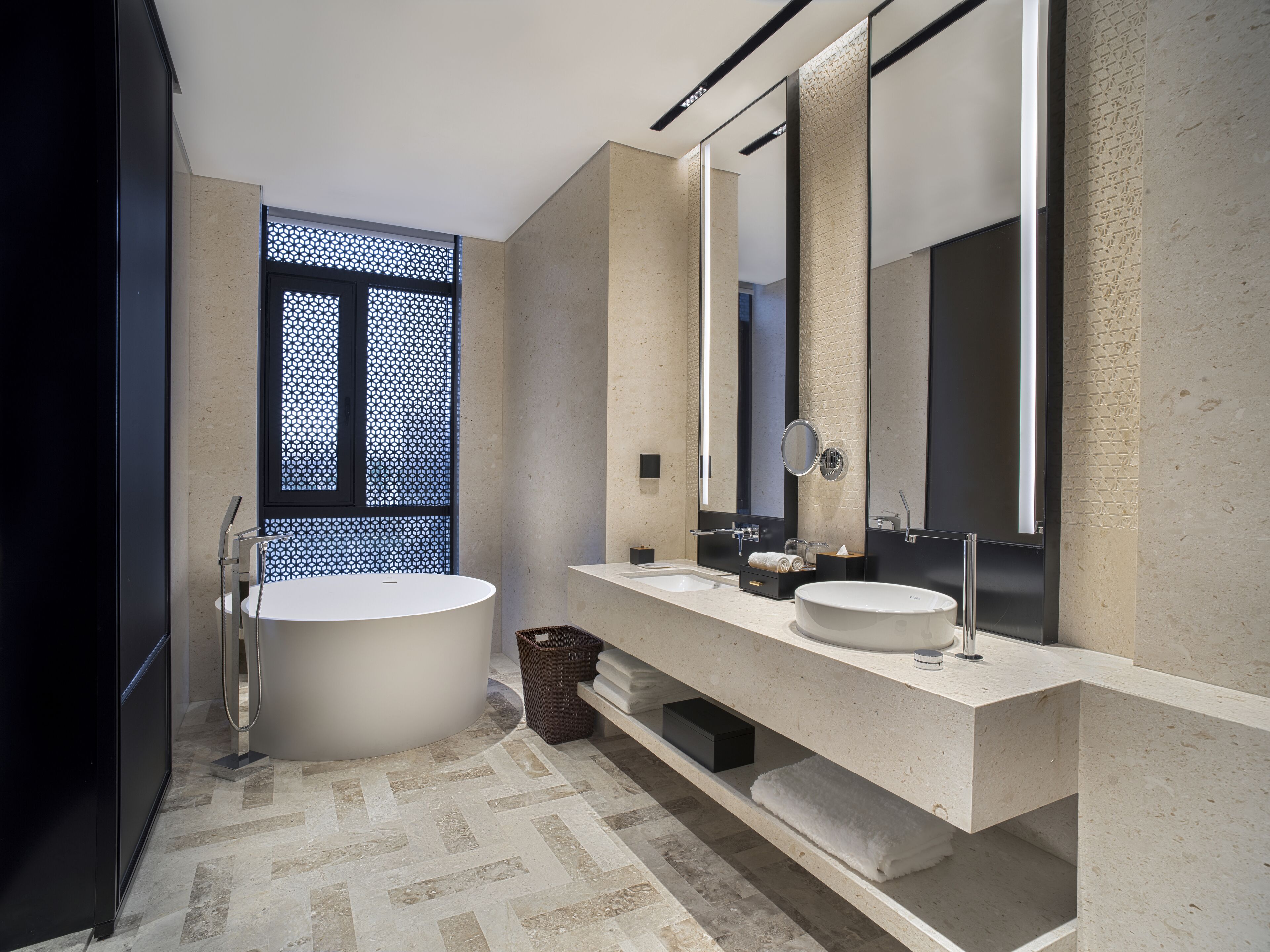 Un baño moderno con una bañera independiente, dos lavamanos y un espejo grande.
