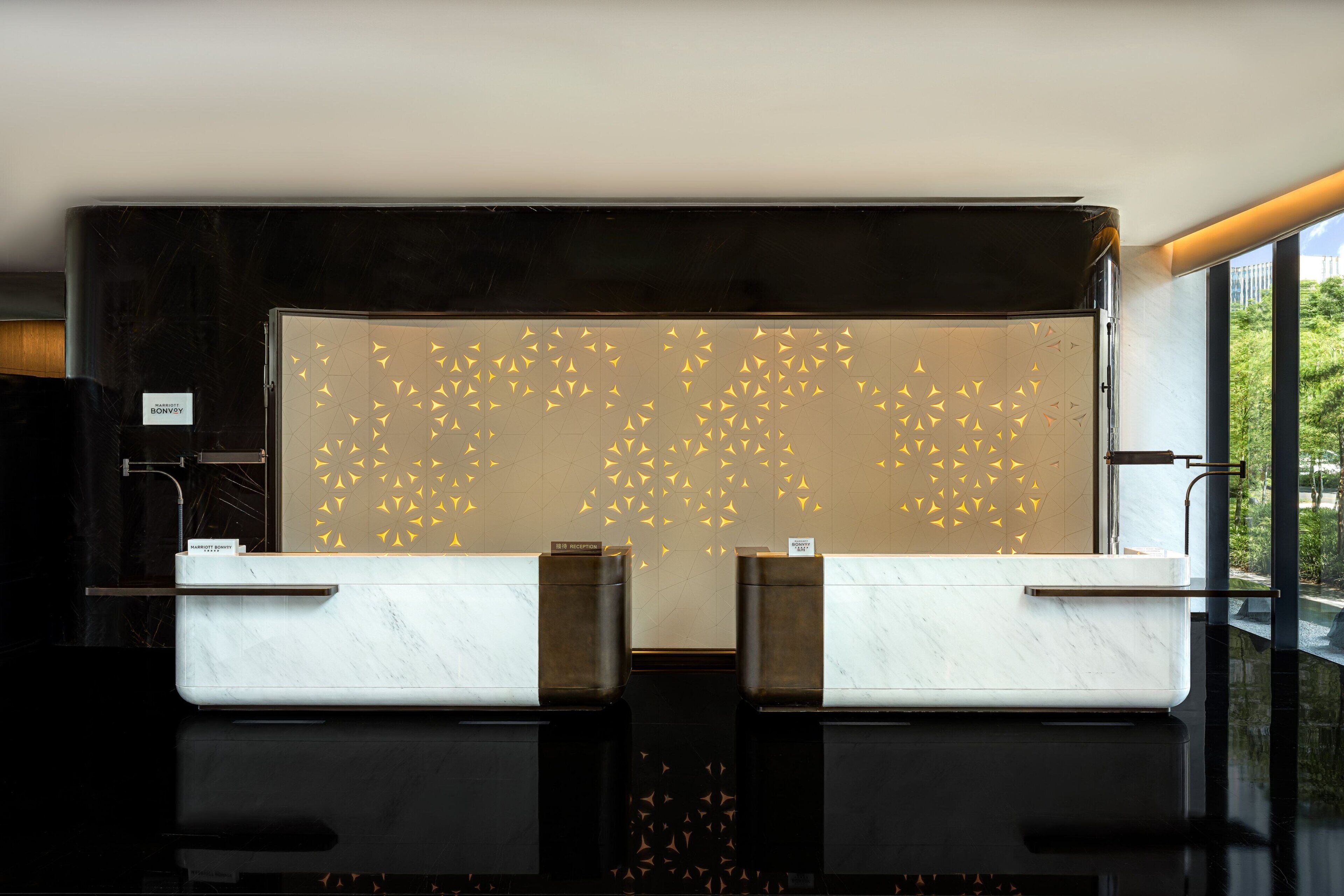 Un mostrador de recepción de diseño moderno, con una encimera de mármol y una pared decorativa con motivos geométricos.