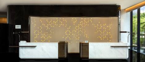 Un mostrador de recepción de diseño moderno, con una encimera de mármol y una pared decorativa con motivos geométricos.