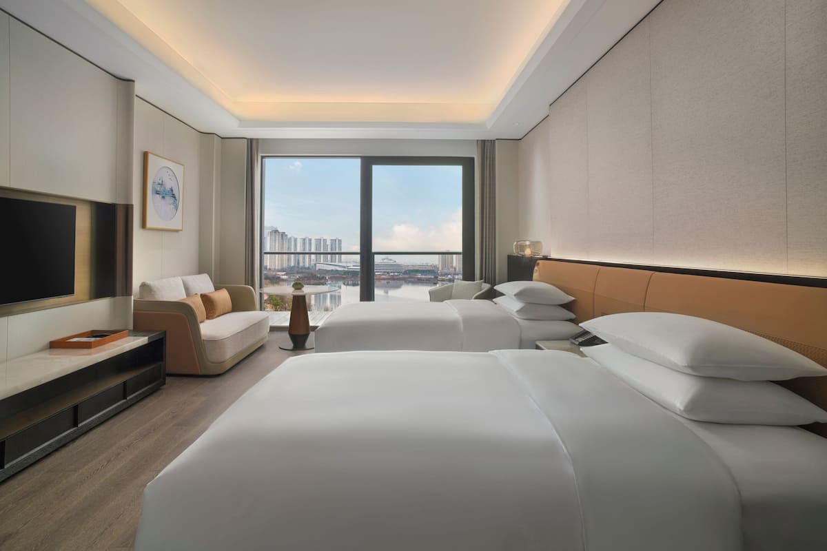 Una camera d'albergo con un letto grande, una poltrona letto, una televisione e vista sulla città.