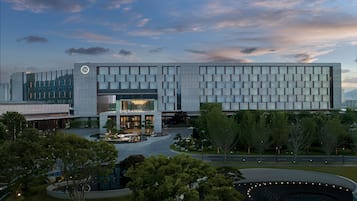 A modern hotel with a large glass facade, a central courtyard, and a landscaped garden area.