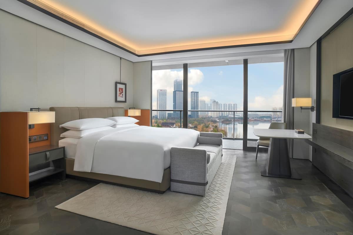 Una camera d'albergo moderna con un letto grande, una scrivania e vista sullo skyline della città.