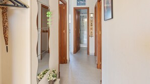 A hallway with wooden doors, a mirror, and a hanging plant.