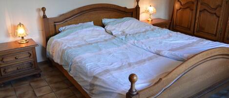 A wooden bed with a headboard, two bedside tables with lamps, and a wardrobe.