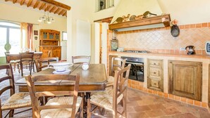 A spacious kitchen with a dining area, featuring a large table and chairs, a built-in oven, and a tiled backsplash. - Belvilla by OYO Lenze (Staffoli)