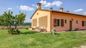 A single-story house with a tiled roof, a brick chimney, and a small garden area with a tree and a bicycle. - Belvilla by OYO Lenze (Staffoli)