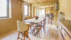 Un coin repas rustique avec une table et des chaises en bois, une grande fenêtre et une cheminée.