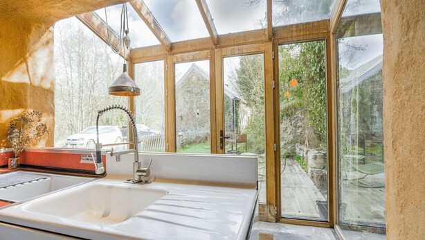 Une cuisine équipée d’un grand évier, d’une cuisinière et d’une fenêtre donnant sur un jardin.