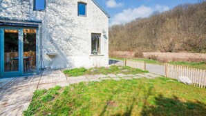 Une maison en pierre avec une porte d’entrée en verre, une petite fenêtre et une clôture en bois.