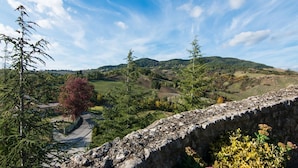 A stone bridge with a pathway leading through a lush valley, surrounded by trees and hills. - Romantic Medieval Escape (Petrella Guidi)