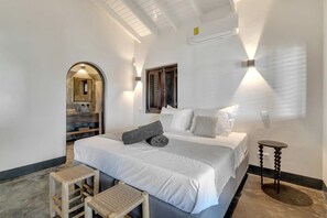 Ein Schlafzimmer mit einem Bett, Nachttischen, einer Bank und einem Spiegel.