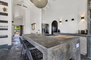 Une cuisine moderne dotée d’un grand îlot central, de tabourets de bar et donnant sur la salle à manger.