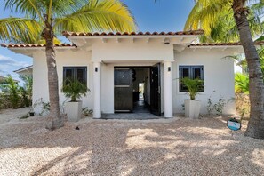 A two-story building with a tiled roof, a central entrance, and potted plants. - Costa de la Luz with pool on Laguna Marina (Kralendijk)