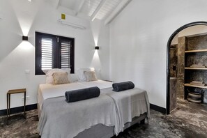 Une chambre à coucher comprenant un lit, des tables de chevet, une fenêtre avec des stores et une bibliothèque intégrée.