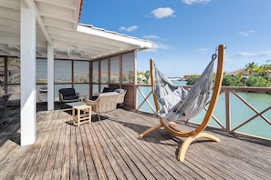 Une terrasse en bois avec un hamac, des chaises et une petite table.
