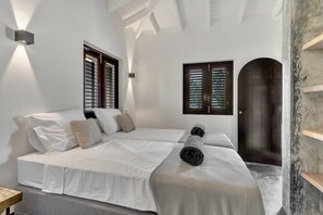 A bedroom with two beds, a wooden door, and a wall-mounted light fixture. - Costa de la Luz with pool on Laguna Marina (Kralendijk)