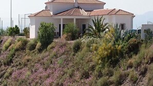 Un bâtiment blanc avec un toit recouvert de tuiles et un jardin à l’avant.