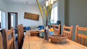 Un coin repas avec une table en bois, des paniers en osier et un vase décoré de branches.