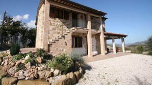 A two-story stone house with a stone staircase, a balcony, and a covered patio area. - Farmhouse Villa w/ Pool (Cagli)