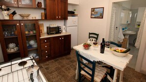 A compact kitchen with wooden cabinets, a microwave, and a dining area with a table set for two. - Cottage in Cisternino with Garden & BBQ (Cisternino)