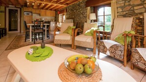 Un interior acogedor con comedor, pared de piedra y vistas al exterior.