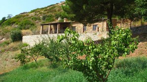 Una casa in pietra con un balcone, immersa nel verde e su una collina.