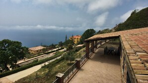 Una terrazza con tetto in tegole, vista sul mare e edifici sullo sfondo.