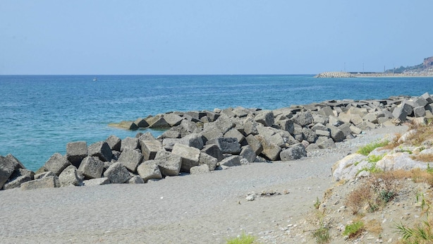 Una costa rocciosa con una vista limpida del mare e una costa lontana.