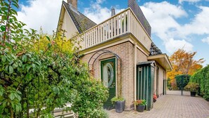 A traditional brick house with a green door, a small porch, and a brick driveway.