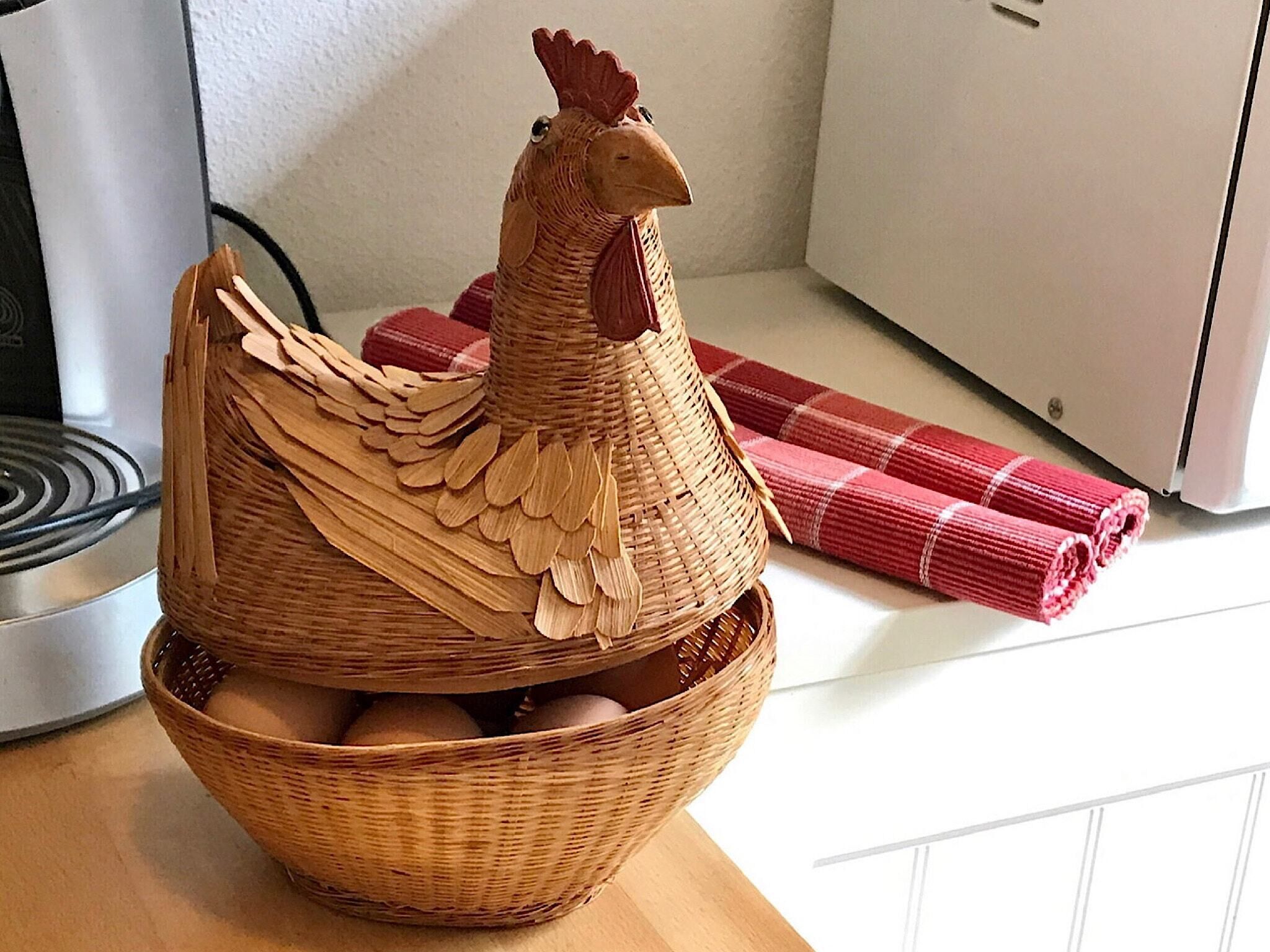 A woven basket with a wooden rooster figure and eggs.