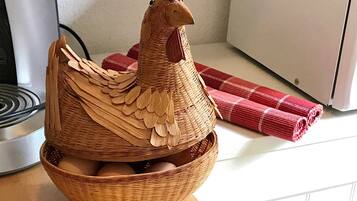 Un panier tressé orné d’une figurine de coq en bois et de quelques œufs.