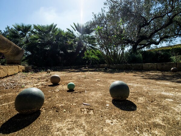 A courtyard with spherical objects, a stone wall, and trees.