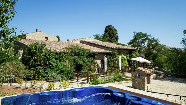 A hot tub in a garden with a stone building in the background. - Charming Countryside Stay (Petralia Sottana)