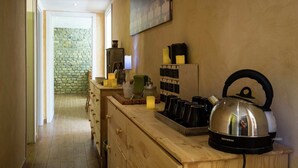 A kitchen with wooden cabinets, a kettle, candles, and a stone wall in the background. - Charming Countryside Stay (Petralia Sottana)